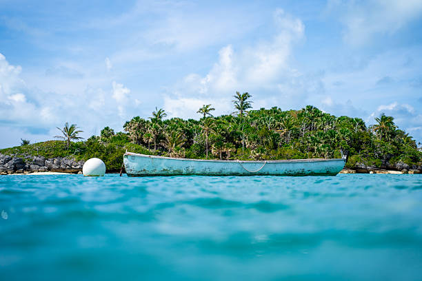 Boat on a Tether Floating in Caribbean Turquoise Waters with Small Island Backdrop