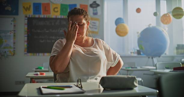 istock Tired Female Teacher Sitting Alone in Empty Classroom, Feeling Stress, Burnout 2228535659