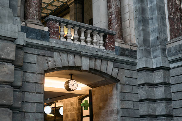 Clock hanging in archway of antwerp central station with marble pillars and balustrade