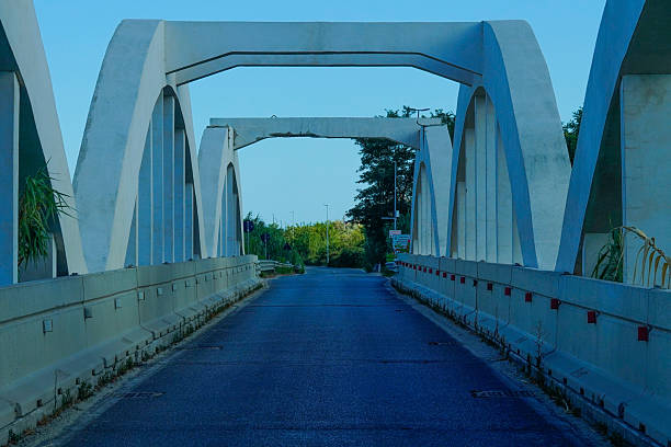 istock The Mussolini-era concrete arch bridge with its symmetrical pattern and open road is a minimalist perspective under a blue sky, ideal for themes related to history, infrastructure or architecture. 2228536376