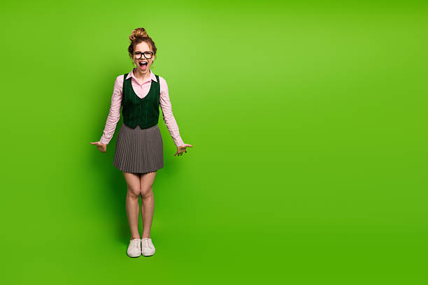 istock Smiling young woman dressed in a school uniform posing on a green background displaying youthful energy 2228536716