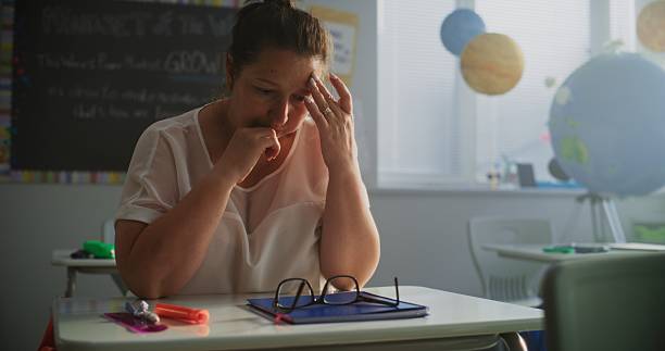 istock Exhausted Female Teacher Sitting Alone at Desk in Empty Classroom, Having Rest After Lesson 2228537293