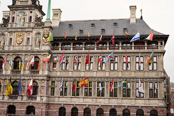 Flags of different countries waving from the facade of antwerp city hall, symbolizing international relations and diplomacy