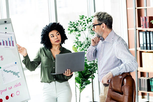 istock Professional business discussion between colleagues in a modern office, analyzing charts and data for a project strategy 2228538428