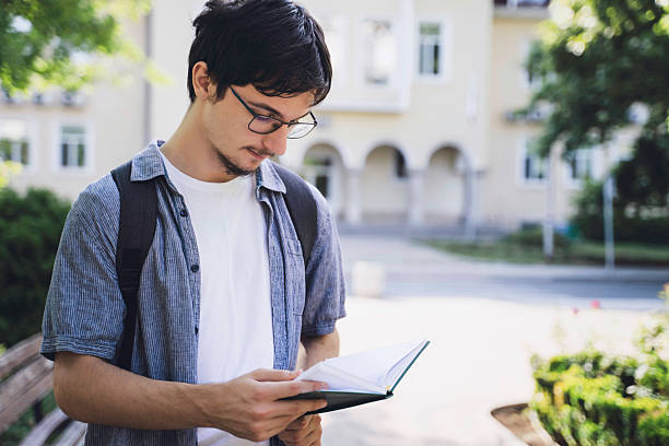 istock Young man reading a book in a tranquil park 2228538566