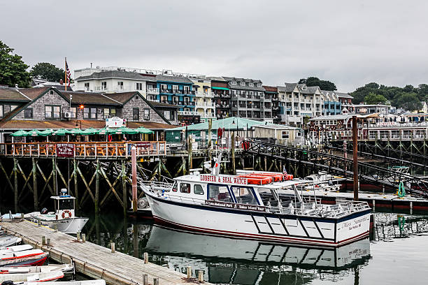 Bar Harbor, Maine USA - July 9, 2013: Waterfront in Bar Harbor, where boats are docked at the marina. Quaint shops line the streets, creating a charming atmosphere on a cloudy day.