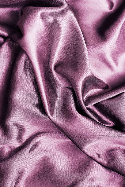 Soft silky fabric in rich mauve hue drapes elegantly across a surface showcasing its texture