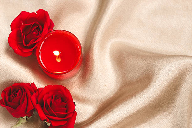 istock Romantic candlelight setup with red roses on a soft golden fabric for a cozy evening 2228540385