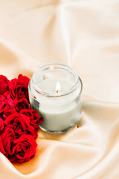 istock Candle glowing among red roses on an elegant satin surface at a romantic gathering 2228540395