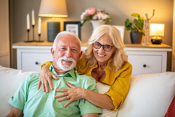 istock Happy senior couple embracing on sofa at home smiling at camera 2228541199