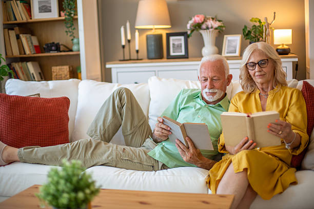 istock Senior couple relaxing on sofa reading books at home 2228541607