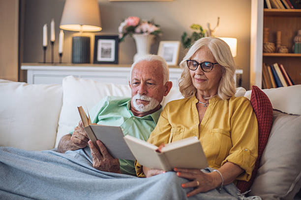 istock Senior couple relaxing on sofa reading books at home 2228542273