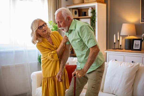 istock Senior man standing up from sofa with walking stick and wife helping 2228543474