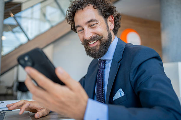 istock Smiling businessman using smartphone in modern office 2228544440