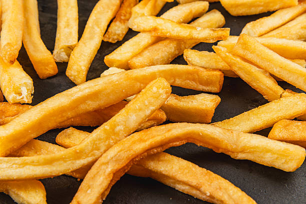 istock Crispy golden fries arranged on a black surface 2228546108