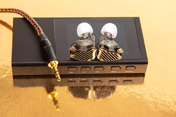 istock Wired earbuds with a stylish braided cable on a black audio player, reflecting on a gold surface. Perfect for tech product shots and music themes. 2228546164