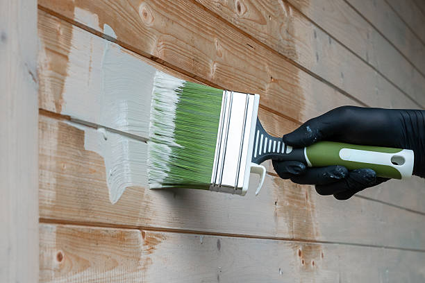 istock Gloved Hand Painting Wooden Surface with Green Handled Brush 2228548262