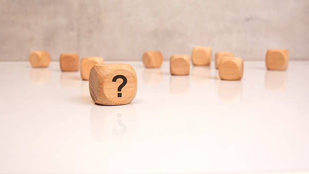 Wooden cube with question mark on white surface, concept of uncertainty or inquiry