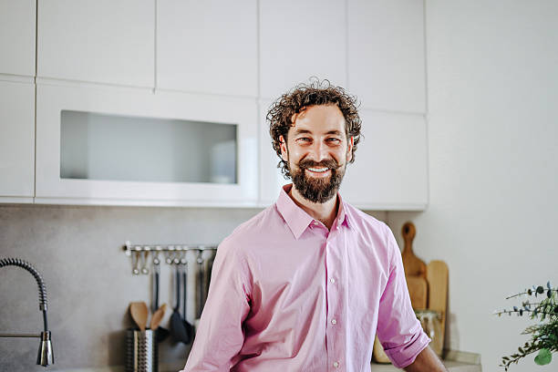 istock Smiling man leaning on kitchen counter in modern home 2228551241