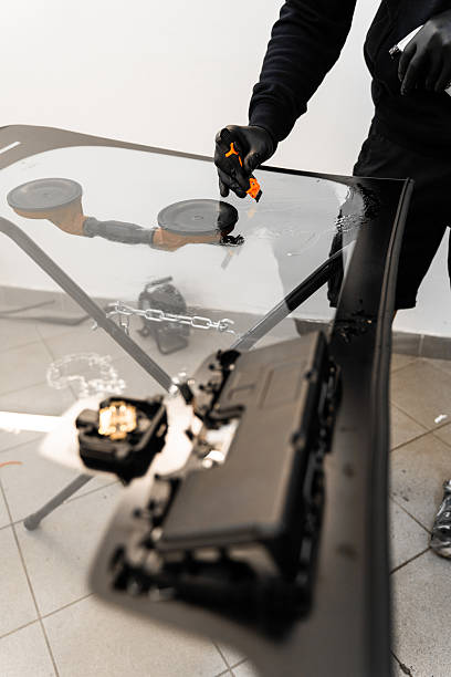 istock Technician scrapes and cleans new windshield after replacement to ensure perfect adhesion. Technician uses scraper to clean the surface of a new windshield post-replacement. 2228551941