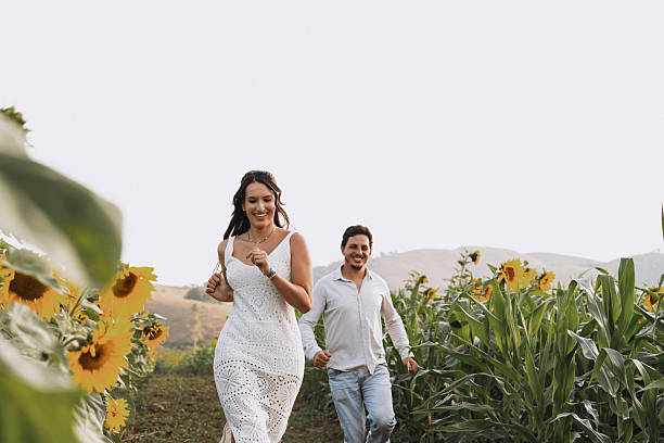Couple walking through sunflower field smiling