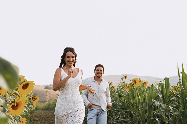Couple walking through sunflower field smiling