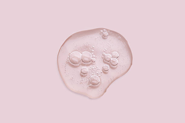 Textured drop of serum with bubbles on pink background.