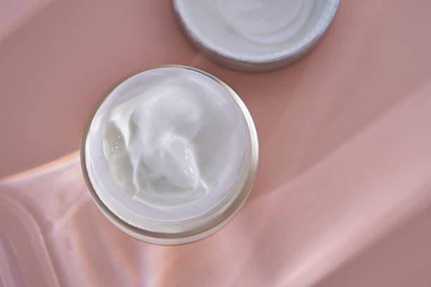 istock An open jar of cream with its texture on a pink background. 2228554748