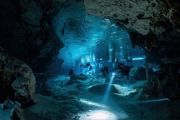 istock Divers explore a stunning underwater cave system illuminated by spotlights. 2228555297