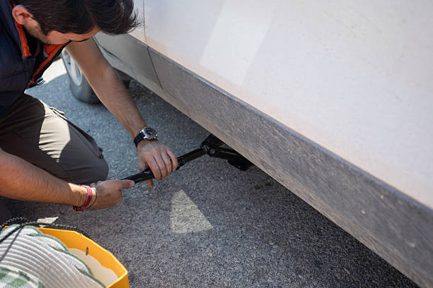 istock Man Using Car Jack to Fix Flat Tire During Roadside Emergency 2228556202
