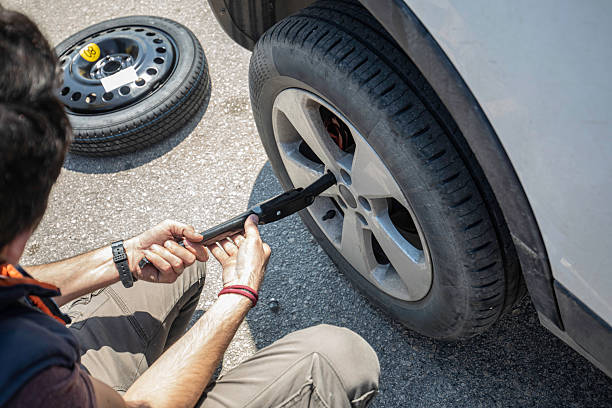 istock Man Changing Flat Tire with Lug Wrench During Roadside Breakdown 2228556242
