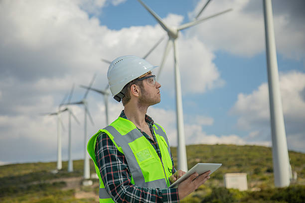 istock Engineer Man with Digital Tablet Inspecting Wind Turbines at a Wind Farm for Renewable Energy and Sustainability 2228557262
