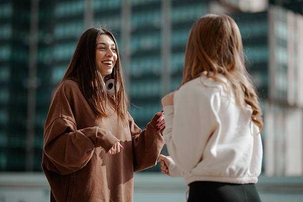 Two women smiling and talking outdoors on a bright sunny day