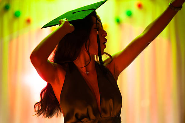 istock Young woman celebrating graduation with expressive gesture beneath vibrant lighting 2228558728