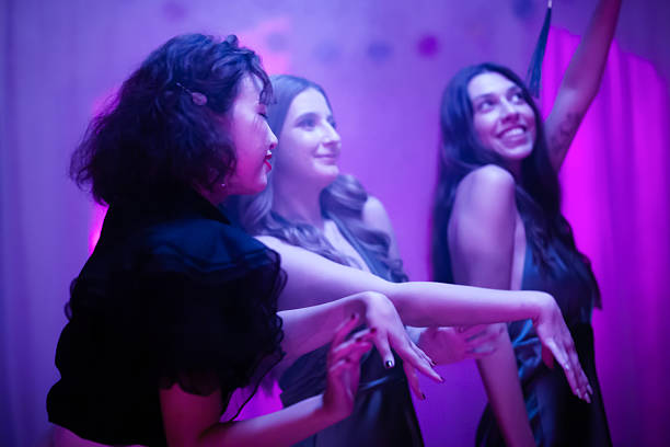 istock Three joyful friends dancing under colorful lights at a festive celebration 2228558759
