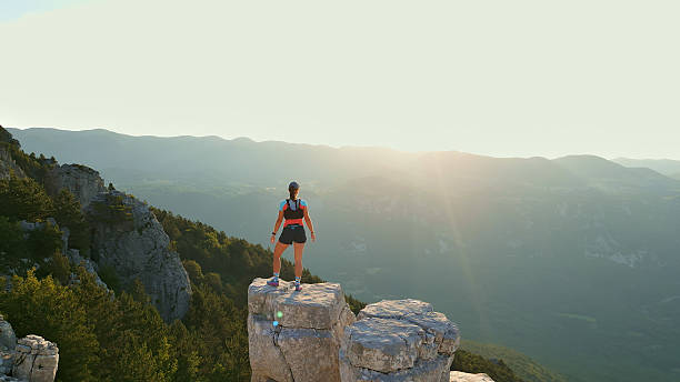 istock Runner Triumphantly Standing on Rocky Peak, Overlooking Mountains 2228559633