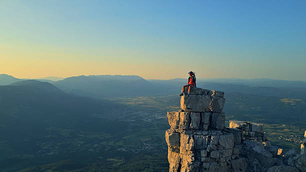 istock Hiker Sits Triumphantly on Cliff Overlooking Sunrise Valley 2228559646