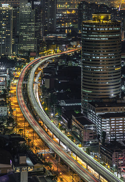 Bangkok, Thailand 20 Dec, 2024 - Nightscape view of with bright glowing lights after sunset. Night scene of light trails of cars on the road of Bangkok city, Long exposure for Light curve lines, use it as your Wallpaper, Poster and Copy space, Selective focus.