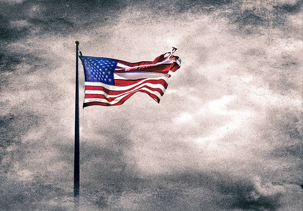 istock Grunge style American flag at flagpole over dramatic cloudy sky 2228573510