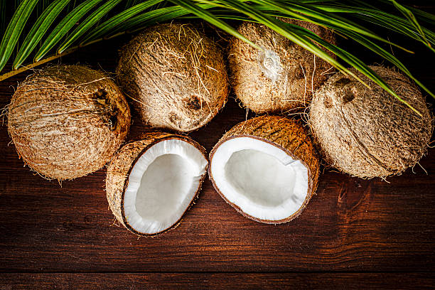 Fruit and vegetable themes:  Low key of coconuts halves on a wooden table