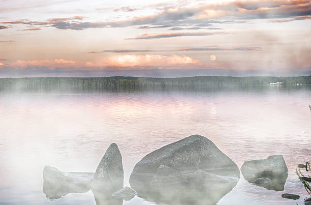 Wooden jetty in the morning in fog, on a Swedish lake. A floating island in the background. Scandinavian nature