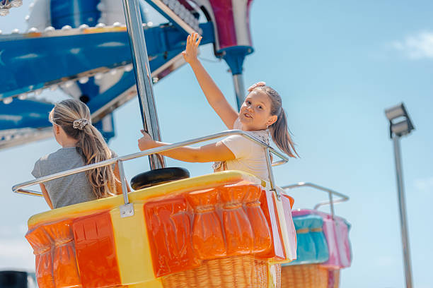 istock Little girl waving hand while riding carousel at amusement park 2228579069