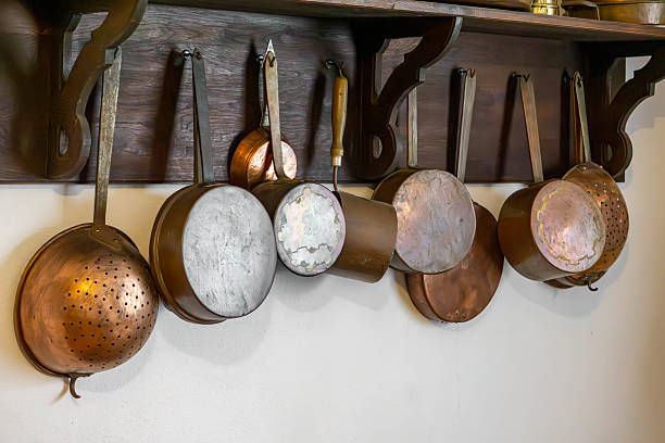 istock Vintage copper pots hanging on a wooden rack in a rustic kitchen. Stylish interior decoration with a touch of vintage charm 2228580935