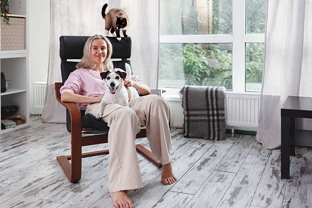Middle age Woman sitting at sofa with Dog and Cat indoors. Concept people and pets