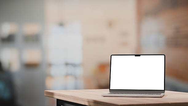 istock Laptop with empty screen on wooden table in cozy living space 2228590523