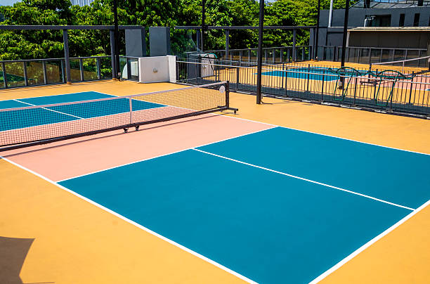 vibrant, freshly painted pickleball court features peach, yellow and blue colors and crisp lines, outdoor sports setting concept