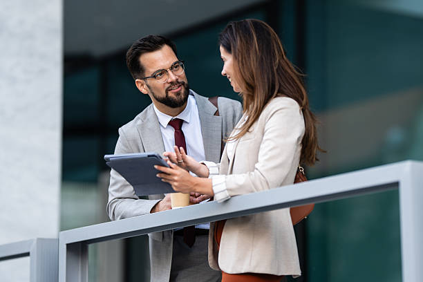 istock Business people using tablet and talking during coffee break outside office 2228596394