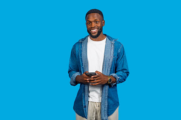 istock Young man using smartphone, smiling and looking away on blue background 2228596641
