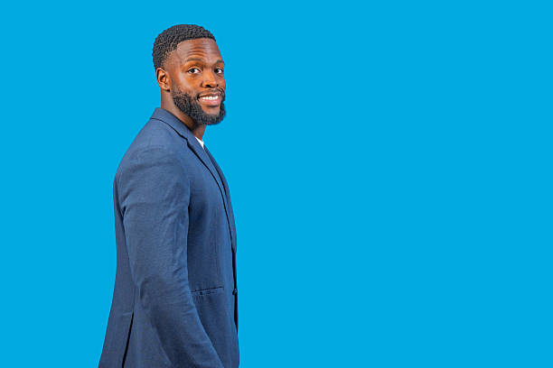 istock Confident businessman smiling over shoulder on blue background 2228596738