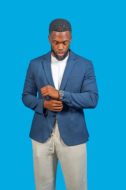 istock Elegant businessman adjusting his sleeve on blue background 2228597251